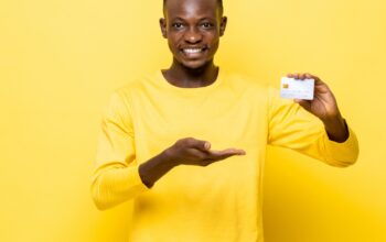 happy-african-man-in-casual-attire-holding-and-presenting-credit-card-picture-id1322272531-b